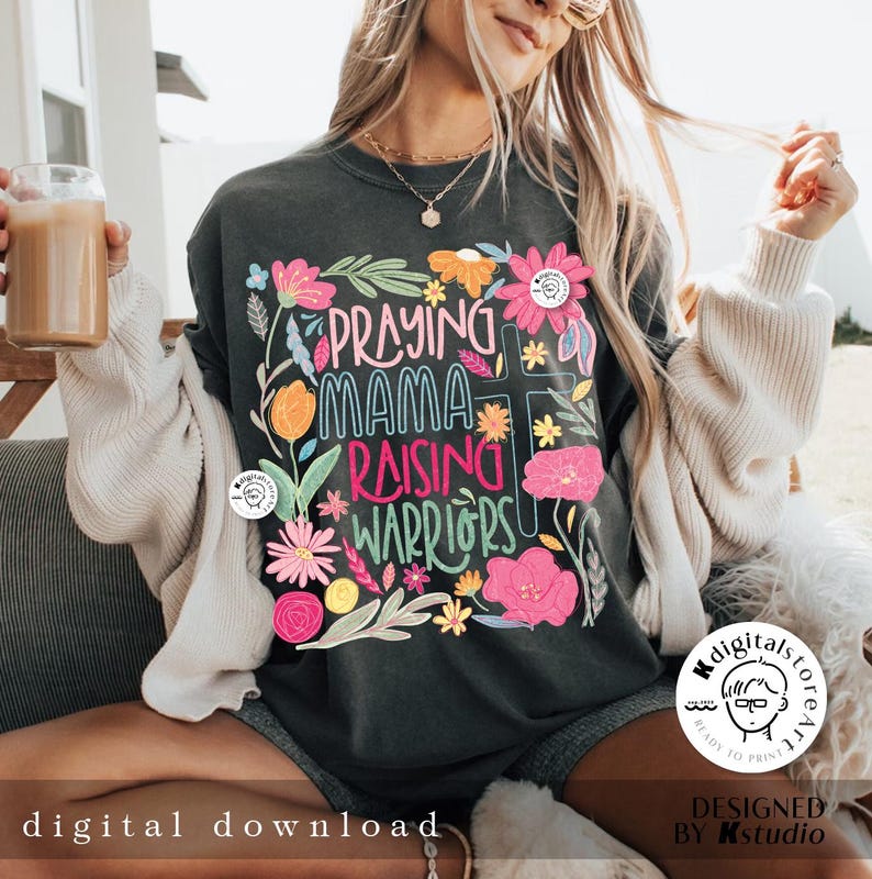May include: A dark gray t-shirt with a floral design and the text "Praying Mama Raising Warriors".