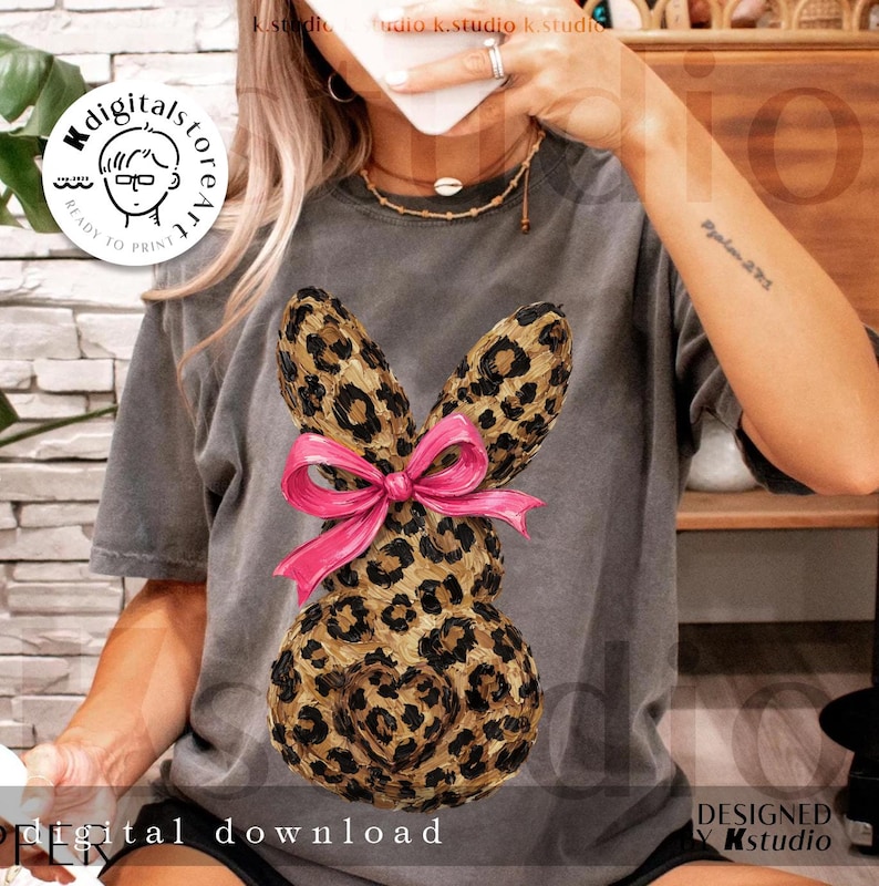 Peut inclure: T-shirt gris avec un motif de lapin l&eacute;opard et un n&oelig;ud rose. Le lapin a un d&eacute;tail en forme de c&oelig;ur. Le texte "digital download" est visible en bas. Design de Kstudio.