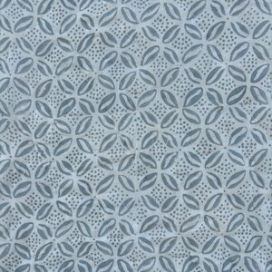 May include: A white fabric with a repeating pattern of blue stylized flowers. The flowers are made up of two overlapping teardrop shapes with a small cluster of dots in the center.