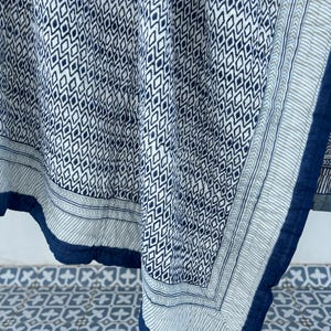 May include: A blue and white cotton quilt with a geometric pattern. The quilt has a blue border and is folded in half.