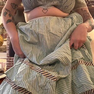 May include: A light green and white striped skirt with a ruffled hem and a crochet top. The skirt has a striped pattern with a contrasting trim. The top is a light green crochet design.