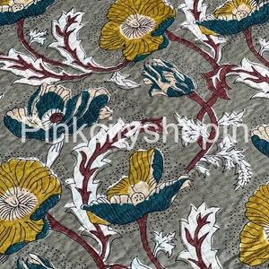 May include: A grey fabric with a floral pattern. The flowers are a mix of teal, yellow, and white. The background is a light grey with a subtle texture.