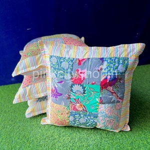 Könnte beinhalten: Ein Stapel von drei bunten Patchwork-Kissenbezügen mit einem gelben und weißen Streifenrand. Die Kissenbezüge sind aus verschiedenen Stoffen mit floralen und geometrischen Mustern gefertigt.
