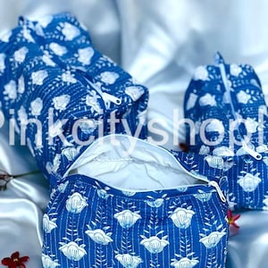 Puede incluir: Tres estuches con cremallera de color azul y blanco con estampado floral. Los estuches están hechos de tela acolchada y tienen un forro blanco. El estuche más grande está abierto y los otros dos están cerrados.