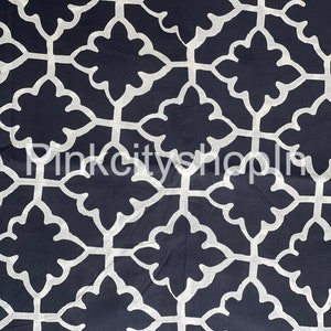 May include: A black fabric with a white geometric pattern of repeating stylised flowers. The pattern is a traditional design.