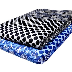 May include: Two folded fabric squares with different patterns. The top square is black and white with a polka dot pattern. The bottom square is blue and white with a swirling pattern.
