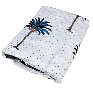 Op de afbeelding: Witte stof met een blauwe en bruine palmboomprint en witte stippen.