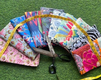 May include: A collection of ten fabric swatches with various colorful floral and geometric patterns. The swatches are arranged in a fan shape and are measured with a yellow tape measure. The tape measure reads from 11 to 42 inches.