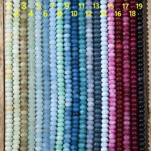 Puede incluir: Diecinueve hilos verticales de cuentas redondas y lisas dispuestas en un degradado de color. Los colores van desde el amarillo pálido, verde claro y varios tonos de azul hasta el rosa, rojo intenso y negro. Cada hilo está numerado del 1 al 19 en amarillo.