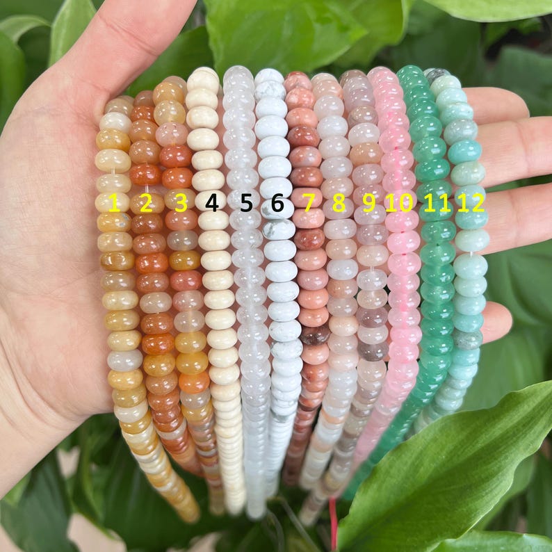 May include: Twelve strands of beads in various colors and materials, including white, beige, pink, and green. The beads are strung on a cord and are numbered 1 through 12.