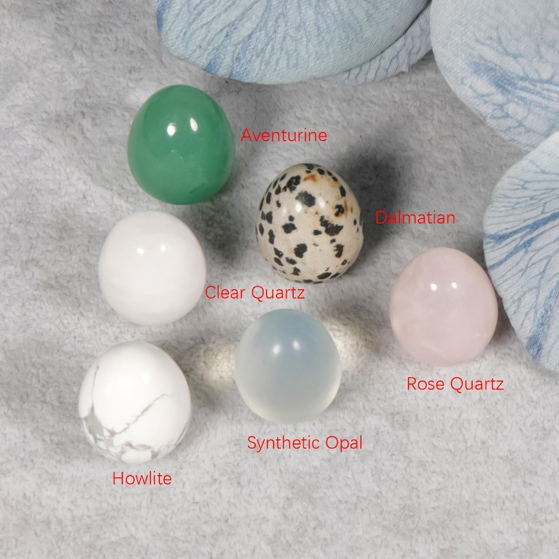 Puede incluir: Una colecci&oacute;n de esferas de piedras preciosas pulidas, que incluyen Aventurina, Cuarzo Claro, D&aacute;lmata, Cuarzo Rosa, Howlita y &Oacute;palo Sint&eacute;tico. Cada esfera es de un color y textura diferentes, con los nombres de las piedras en texto rojo.