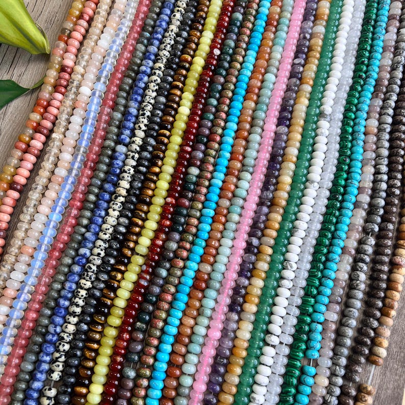 May include: Assortment of colorful gemstone beads, including turquoise, green, red, yellow, and white. The beads are strung on a string and are ready to be used for jewelry making.