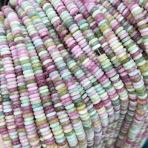 May include: A strand of multi-colored gemstone beads. The beads are round and have a smooth, polished finish. The colors of the beads include pink, green, and white.