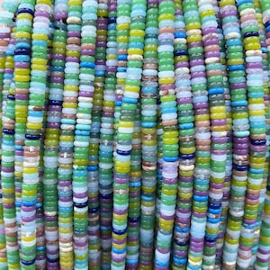May include: A strand of colorful round beads made of various types of stone. The beads are arranged in rows and are a mix of green, blue, yellow, purple, and white.