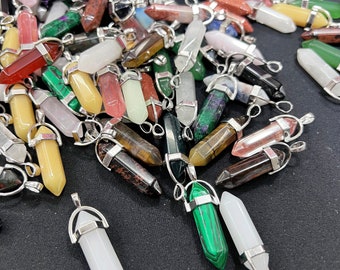 May include: A collection of colourful crystal point pendants with silver metal caps and loops. The pendants are made of various types of gemstones, including amethyst, rose quartz, tiger's eye, and green aventurine.