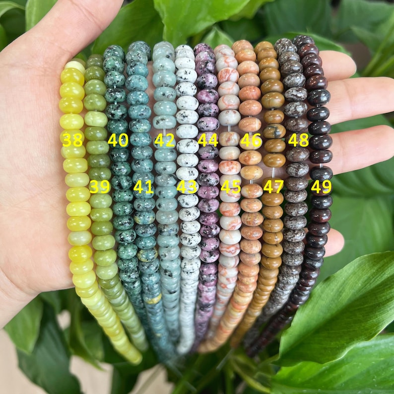 May include: A collection of 12 strands of round, colorful, speckled beads. The beads are arranged in a row, with the numbers 38 through 49 printed on the beads. The beads are made of various materials, including stone, glass, and wood.