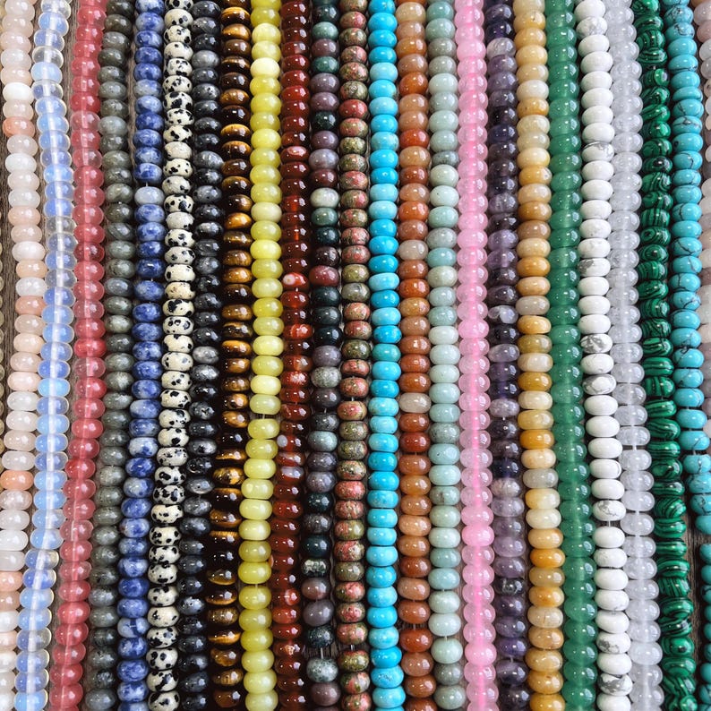May include: Assortment of colorful gemstone beads, including turquoise, green, pink, white, and brown. The beads are strung on a string and are ready for jewelry making.