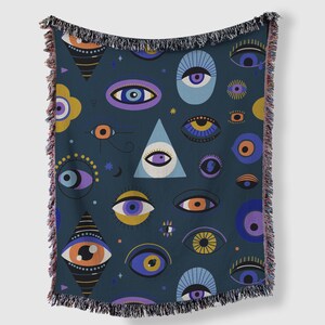May include: Dark blue throw blanket with a repeating pattern of stylized eyes in various colors, including orange, purple, and yellow. The blanket has a fringed edge and a geometric design. The overall theme is mystical and bohemian.