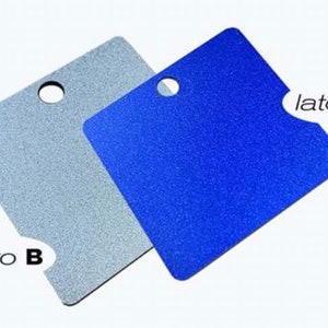 Può includere: Due pezzi di materiale quadrati, uno argentato e uno blu, con un foro al centro. Il pezzo argentato ha il testo "lato B" nell'angolo in basso a destra, e il pezzo blu ha il testo "lato A" nell'angolo in alto a destra.