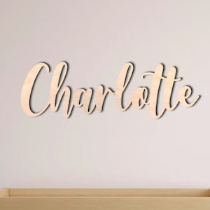Könnte beinhalten: Ein Holzschild mit dem Namen "Charlotte" in kursivschrift.