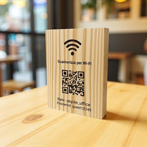 Peut inclure: Un panneau rectangulaire en bois avec un symbole Wi-Fi, un code QR et du texte. Le texte comprend "Scannerizza per Wi-Fi", "Rete: ospite_uffice" et "Password: guest12345". Le panneau est sur une table en bois clair.