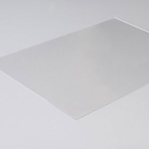 Può includere: Un foglio di plastica trasparente e chiaro. Il foglio è liscio e ha una leggera lucentezza.