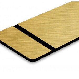 May include: A gold brushed metal sign with a black border. The sign is rectangular and has a brushed metal finish.