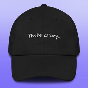 May include: Black baseball cap with the embroidered phrase "That's crazy..." in white. The cap has a curved brim and a fabric strap closure at the back. The hat is a classic style, suitable for casual wear.