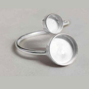Op de afbeelding: Zilveren ring met twee ronde, bezel-gezet blanks. De ring is verstelbaar en kan aan elke vinger worden gedragen.