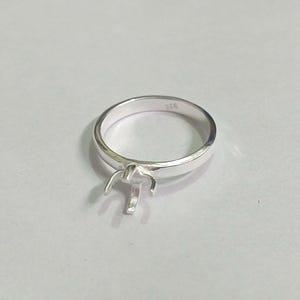Op de afbeelding: Een zilveren ring met een klauwbezetting voor een edelsteen. De ring is gemarkeerd met het nummer "925" aan de binnenkant van de band.