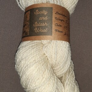 May include: A ball of off-white yarn labelled "Spotty and Splash Wool" with a description of "Description: Light Weight: 50g Code: 1182 Price: &pound;6.50"