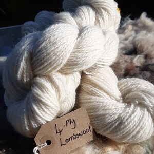 May include: A skein of white 4-ply lambswool yarn with a brown tag that reads "4-ply Lambswool".