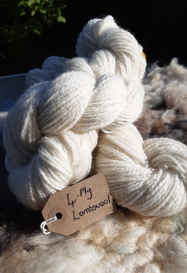 May include: A skein of white 4-ply lambswool yarn with a brown tag that reads "4-ply Lambswool".
