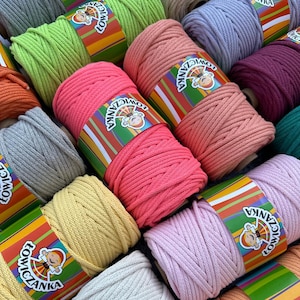 Peut inclure: Plusieurs bobines de fil macramé coloré, dans des tons de rose, vert, jaune et bleu. Chaque bobine est enveloppée d'une étiquette avec une illustration de dessin animé et le texte "ŁOWICZANKA".
