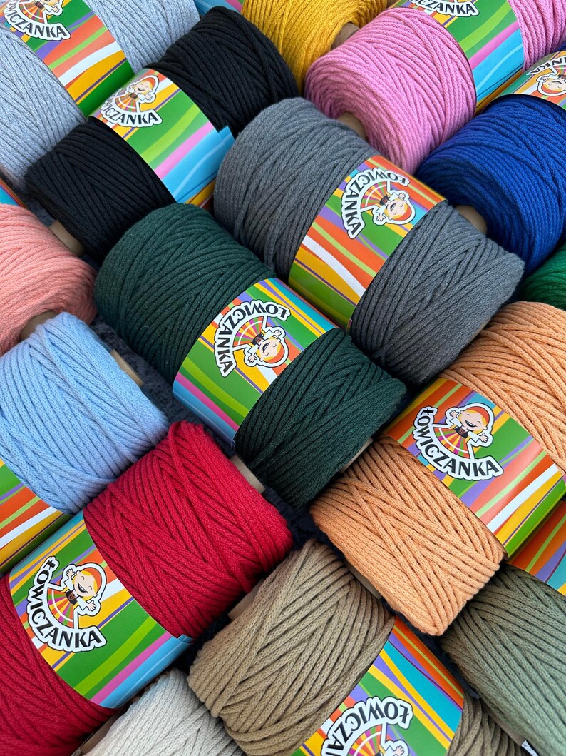 May include: A selection of macrame cord spools in a variety of colours, such as pink, blue, green, and red. Each spool is wrapped with a label featuring a cartoon character and the brand name. The cords are tightly wound, indicating a high-quality crafting material.
