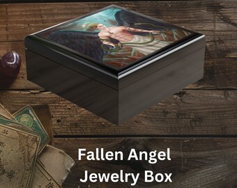 May include: A black wooden jewelry box with a square lid featuring a colorful illustration of a fallen angel with wings spread wide. The text "Fallen Angel Jewelry Box" is printed below the image.