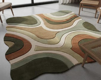 May include: A large, abstract area rug with a flowing, organic design. The rug features a palette of earthy tones, including shades of green, brown, beige, and white. The pattern resembles layered, undulating shapes, creating a modern and artistic aesthetic.