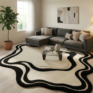 May include: A modern living room featuring a large, abstract rug with a cream-colored base and bold black wavy lines. A gray sectional sofa, glass coffee table, and potted plant complete the contemporary decor.