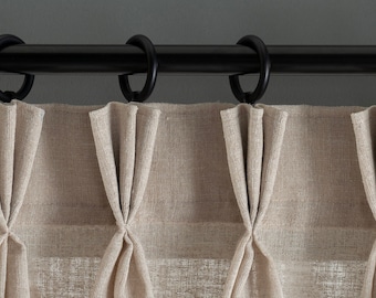 May include: Beige curtains with pleats hanging from a black curtain rod with rings.