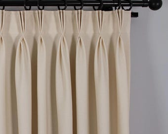 May include: A set of off-white curtains with pleats hanging from a black curtain rod.