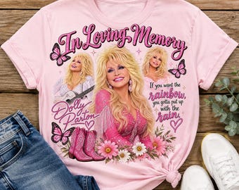 May include: A light pink t-shirt featuring a graphic print of Dolly Parton with the text In Loving Memory, Dolly Parton, and If you want the rainbow, you gotta put up with the rain. The design includes pink butterflies, flowers, and boots.