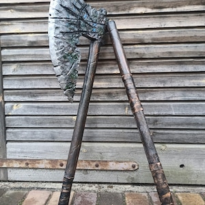 May include: A large, silver axe with a wooden handle. The axe head has a textured surface and a curved blade. The handle is wrapped in brown leather.