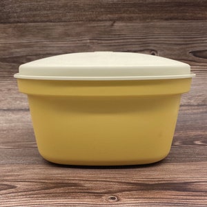 May include: A yellow plastic bowl with a white lid. The bowl is round and has a smooth surface.