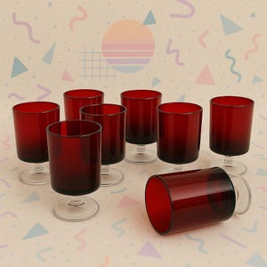 May include: A collection of eight ruby red stemmed glasses. The glasses have a cylindrical shape with a clear stem and base. One glass is lying on its side. The background has a retro design with pastel colours.