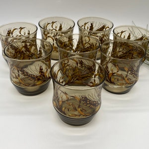 May include: Set of eight brown glass tumblers with a wheat design. The glasses have a rounded bottom and a wide mouth.