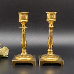 Peut inclure: Une paire de bougeoirs en métal doré avec des bases carrées et un design simple.