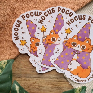 May include: Three sticker sheets with a cartoon cat wearing a purple wizard hat and holding a magic wand. The text on the stickers says "Hocus Pocus I cannot focus".