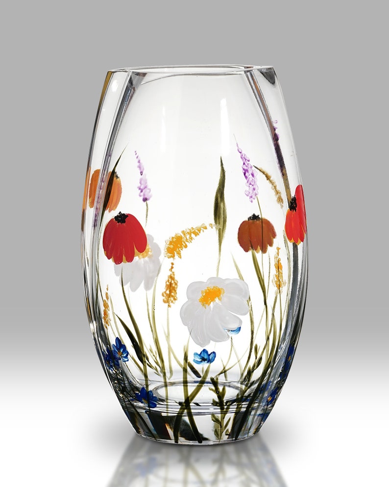 May include: A clear glass vase with a hand-painted design of colorful wildflowers. The vase has a rounded, oval shape and a slightly flared opening.