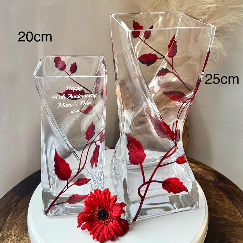 May include: Two clear glass vases with red leaf designs. The taller vase is 25 cm tall and the shorter vase is 20 cm tall. The shorter vase has the text "Happy 40th Anniversary Mum & Dad xxx" engraved on it.