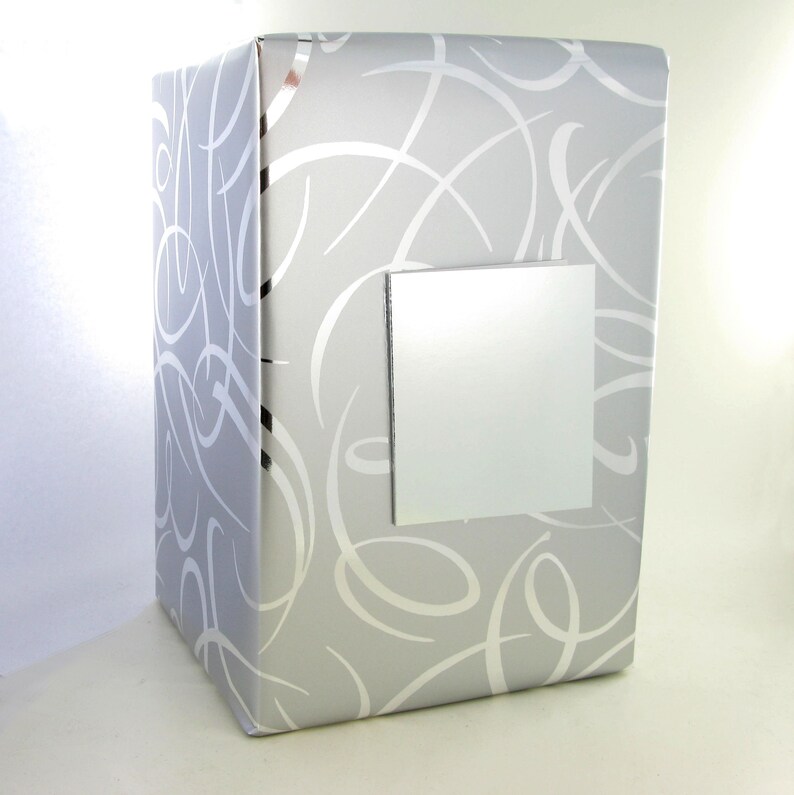 May include: A silver gift box with a white swirl pattern and a blank silver label.